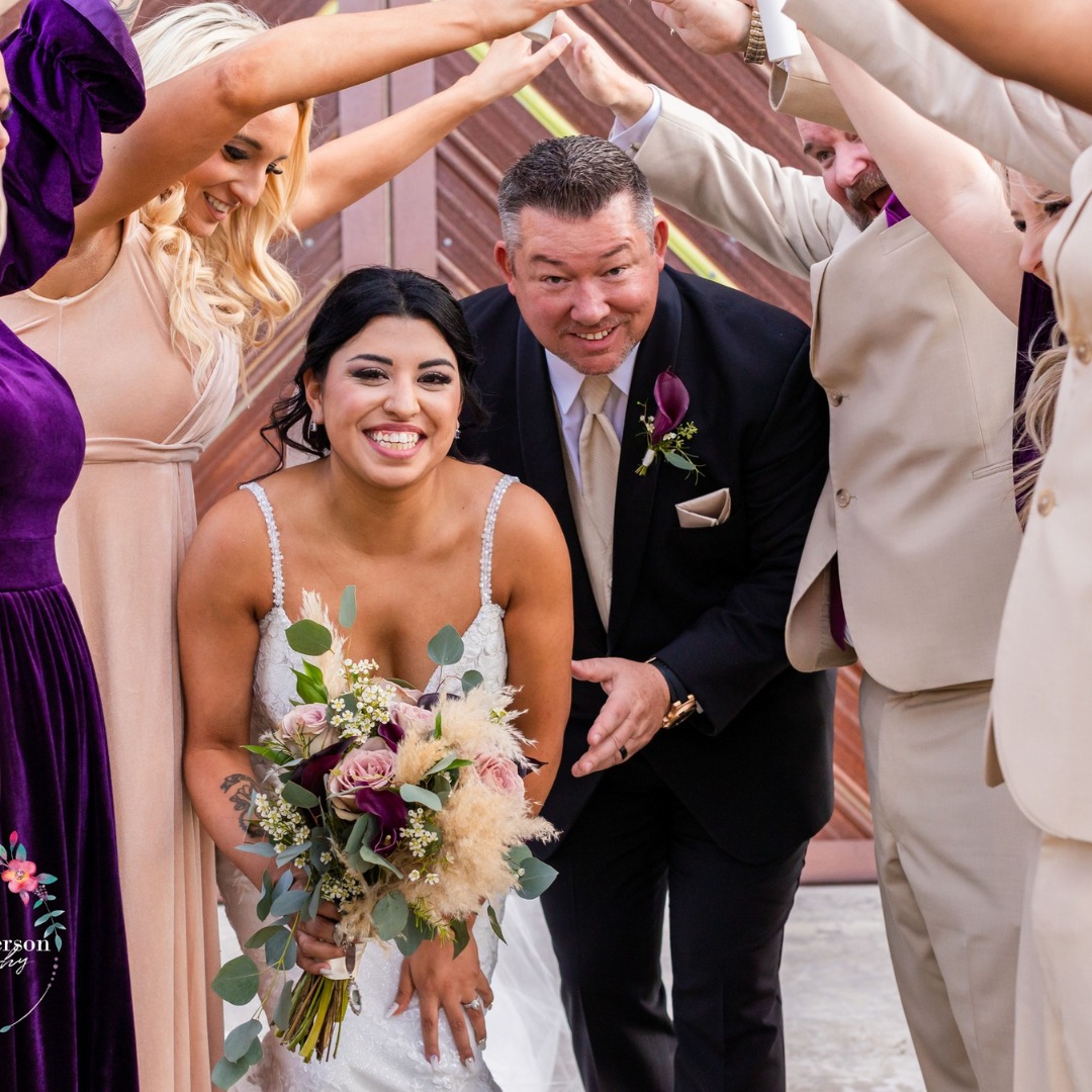 bride and groom walking through wedding party's arms