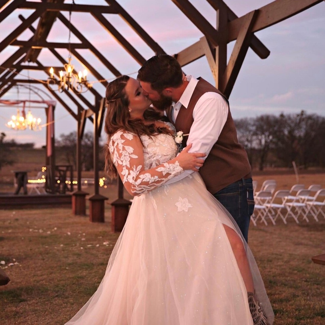 couple kissing under large pergola at sunset